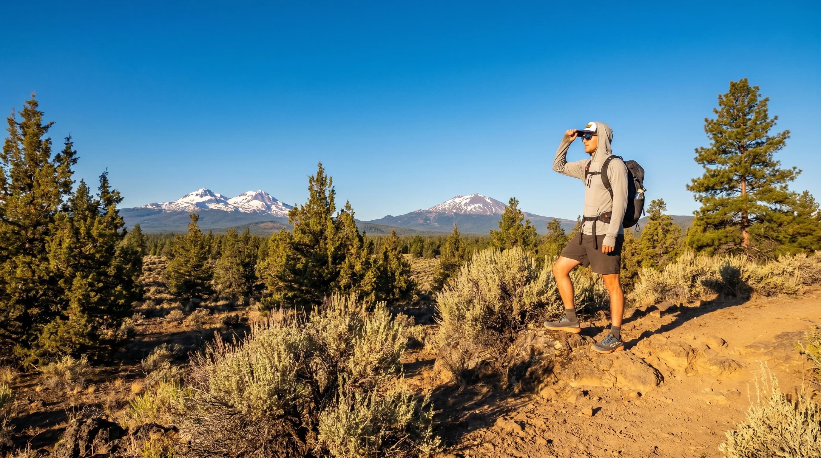 A hiker in a hat and sunglasses on an exposed sunny high-desert trail near Bend