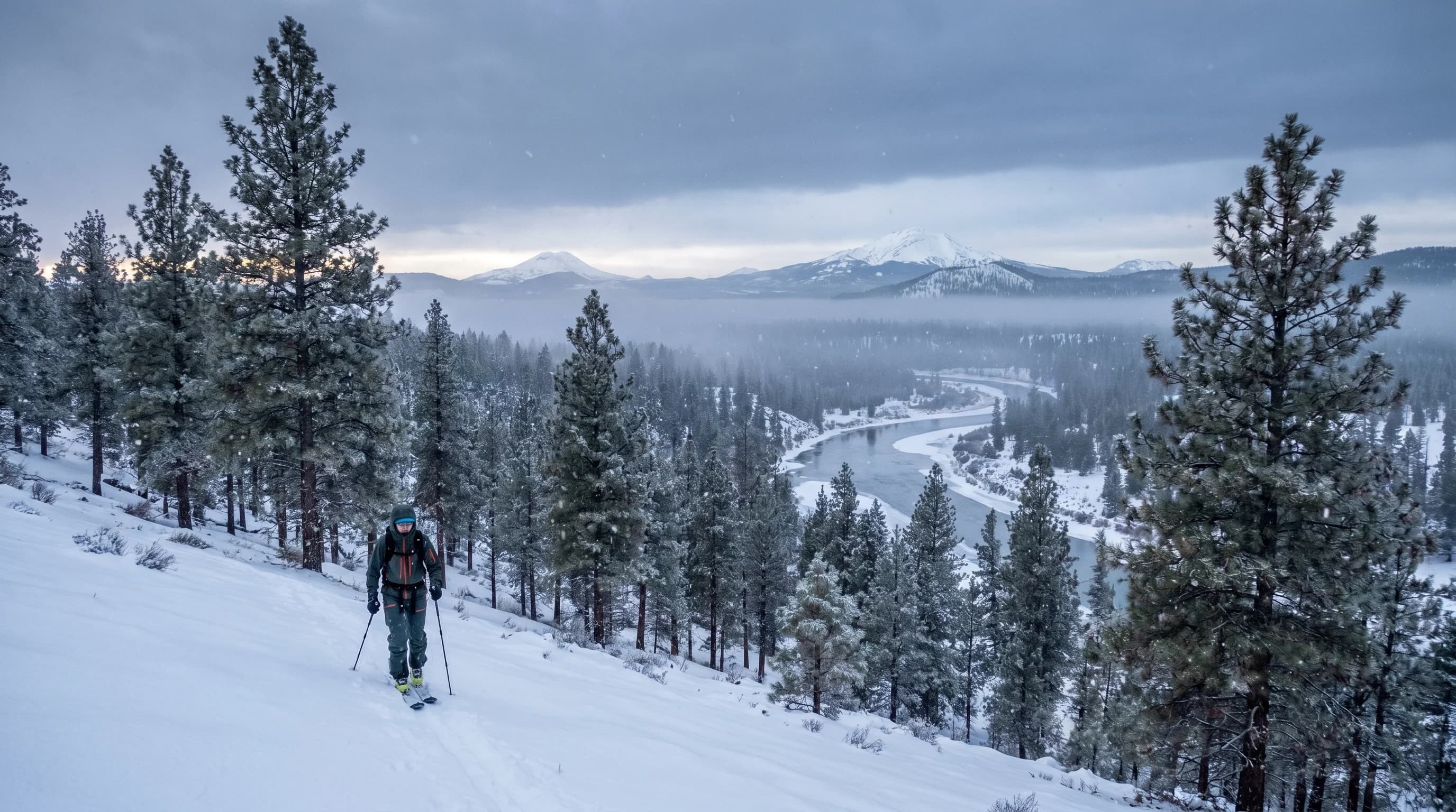 A snowy December evening in Bend with holiday lights and the Cascades behind