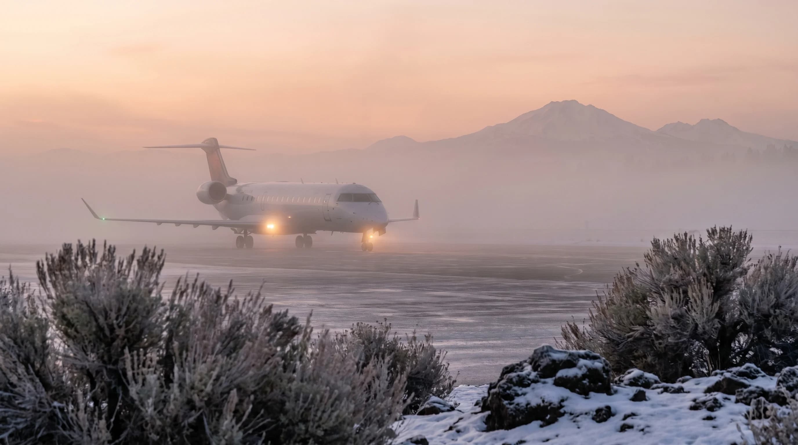 A regional jet on the Redmond airport tarmac in winter freezing fog at dawn with low visibility