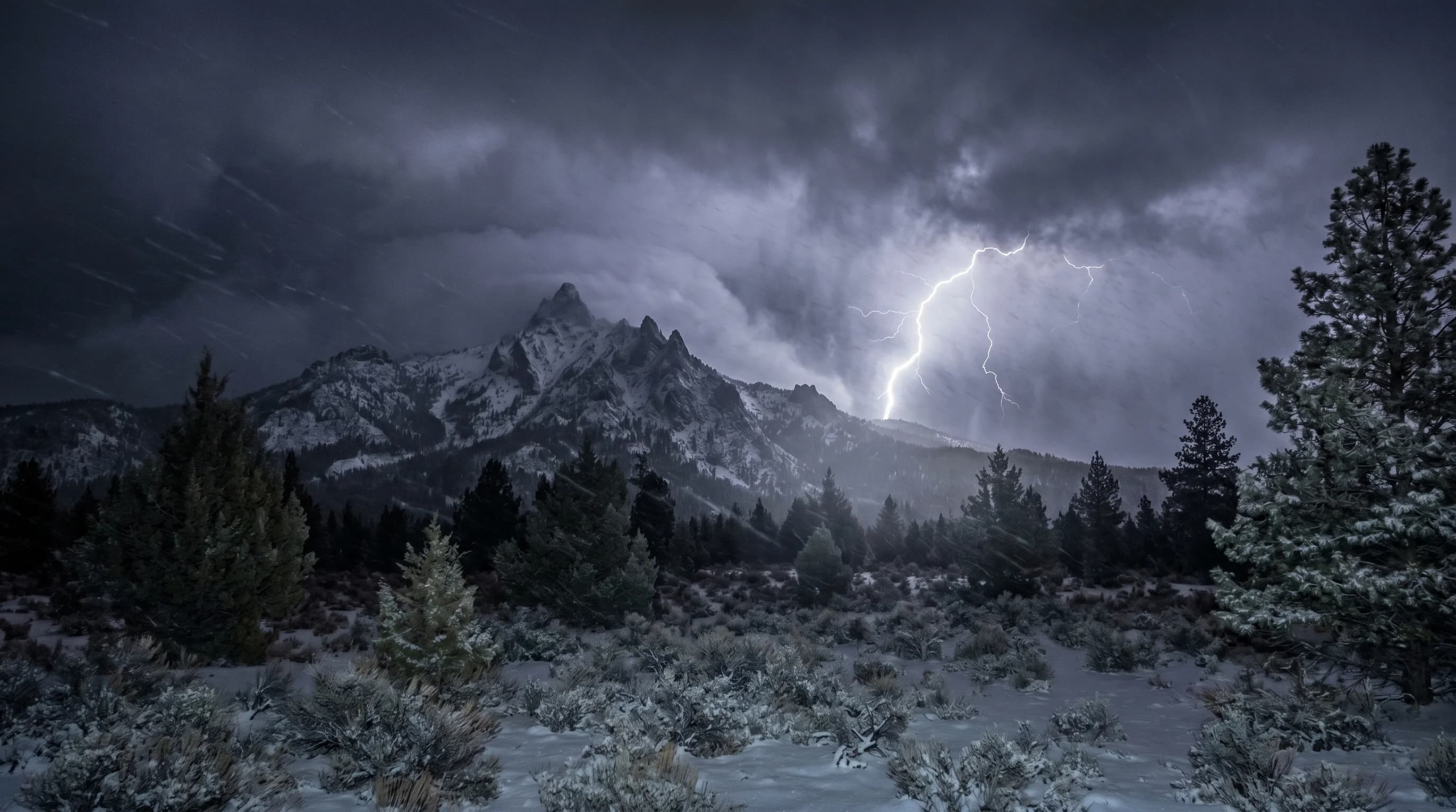 Lightning flashing through heavy falling snow at night over a Cascade peak during thundersnow