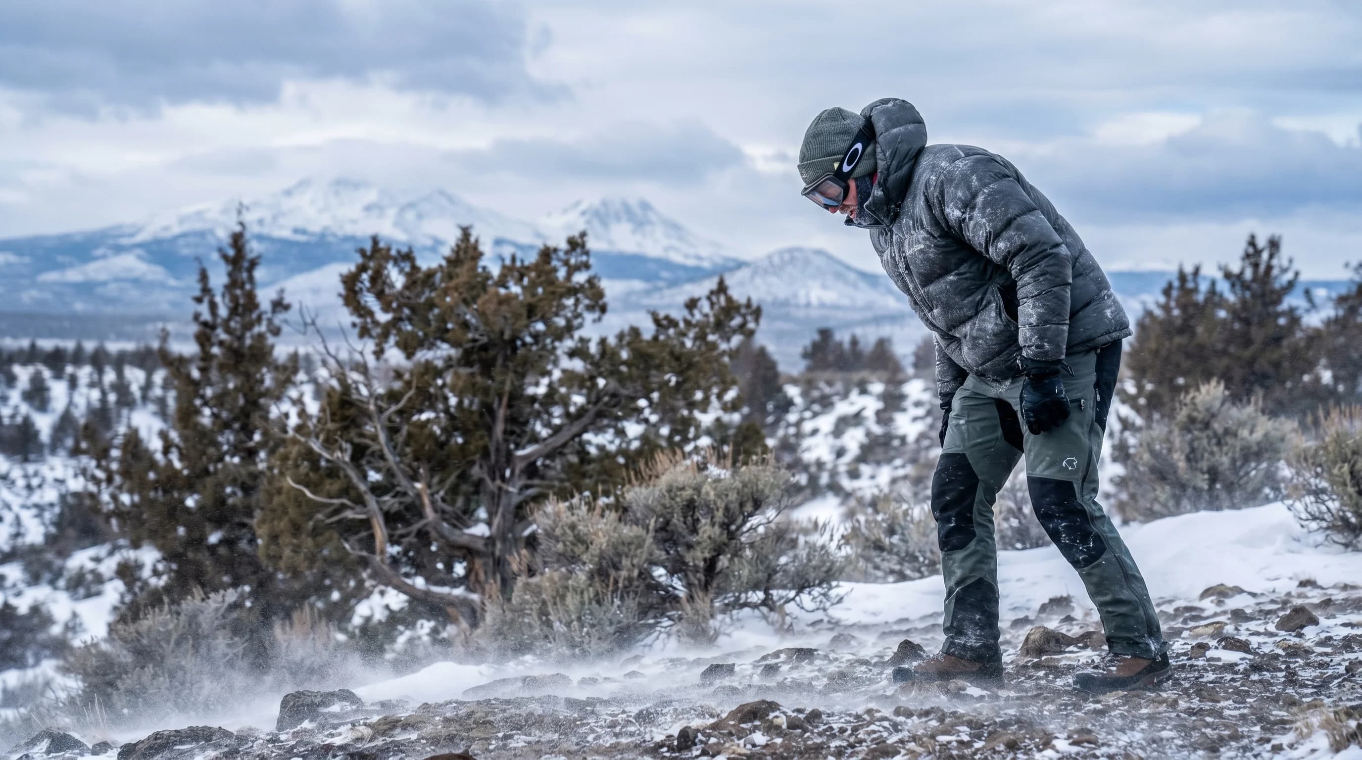 A bundled person leaning into blowing wind and snow on an exposed Central Oregon ridge