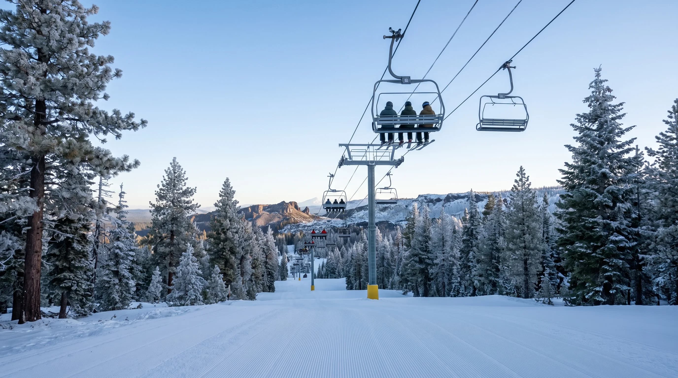 A chairlift above a freshly groomed run with rime-frosted trees on a clear early-season morning